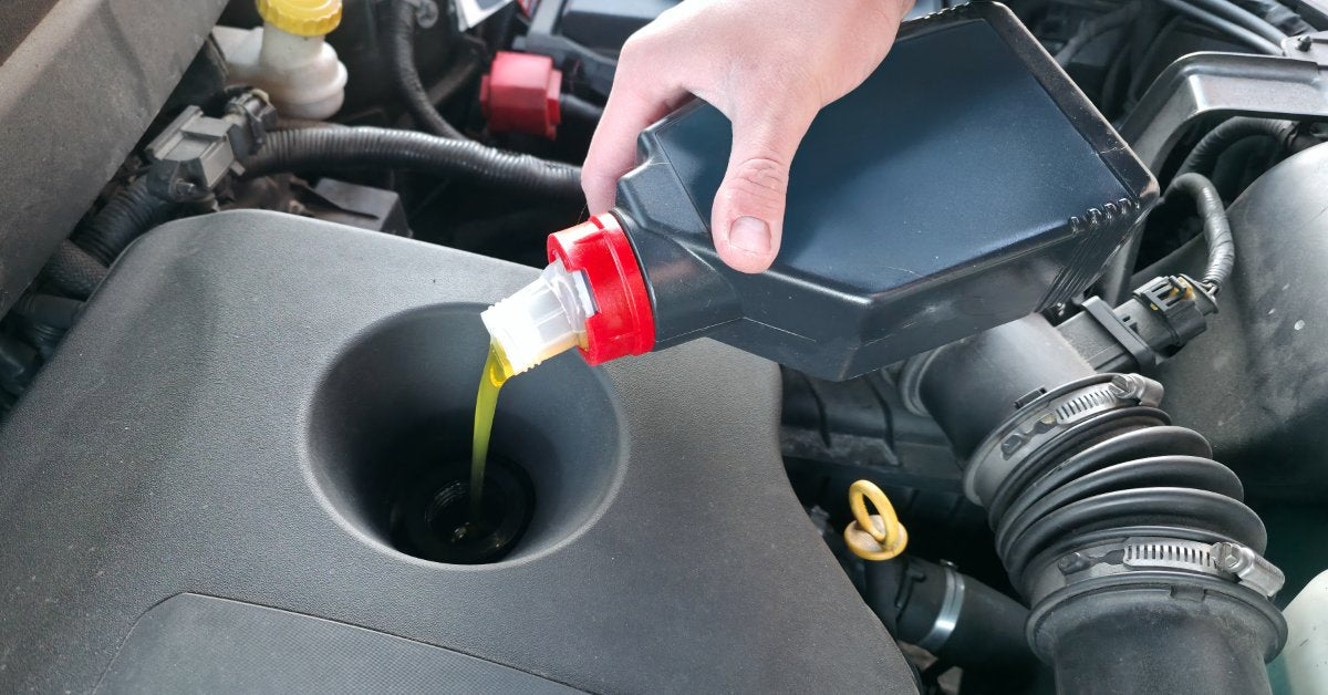 Technician pouring fresh motor oil into a vehicle engine during routine maintenance to support performance and engine protection.