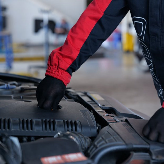Automotive technician applying an engine treatment product during vehicle maintenance to support engine performance and protection.
